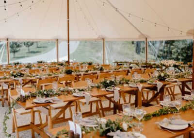 Wooden table and chair hire with green foliage table decoration within a wedding event marquee