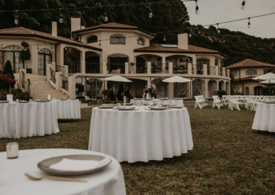 Outdoor dining and white chairs laid out for a ceremony outside a wedding venue