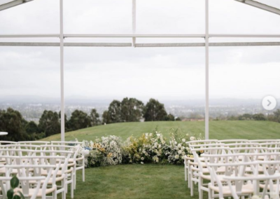 Wedding ceremony within a clear marquee with white chair hire