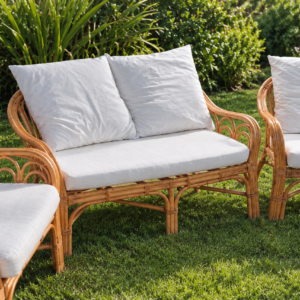 Wicker outdoor sofa and two armchairs with white cushions on a sunny lawn.